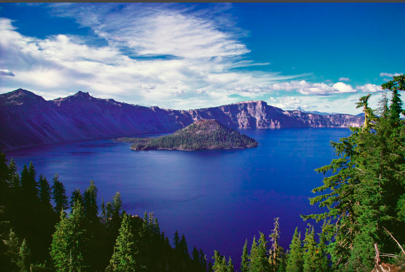 A showcase nature image featuring a lake with a small island inside surrounded by montains and beauitful skies.